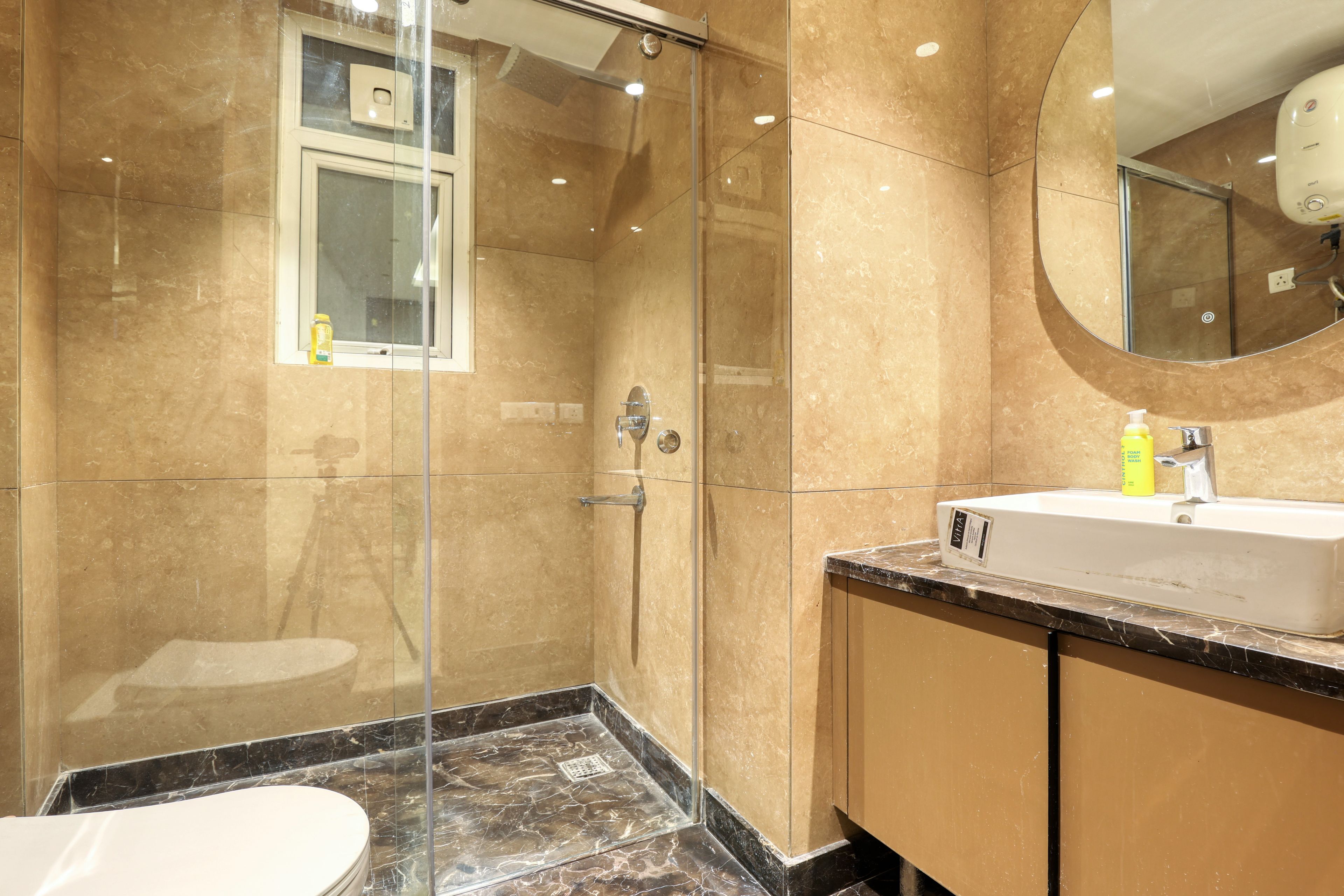 Un baño moderno con ducha de vidrio, lavamanos con espejo y un inodoro.