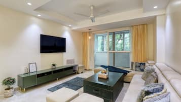 A modern living room with a flat-screen TV, a green entertainment unit, a sofa, and a coffee table.
