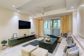 A modern living room with a flat-screen TV, a green entertainment unit, a sofa, and a coffee table. - THE LUTF (New Delhi)
