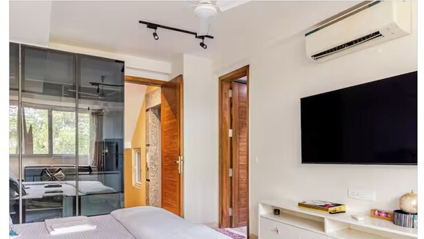 A modern bedroom with a bed, a TV, a desk, and a wardrobe.