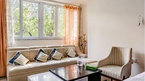 A living room with a sofa, a coffee table, and a striped armchair.