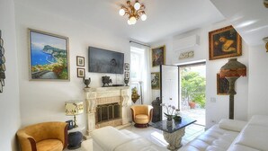 Ein geräumiges Wohnzimmer mit Kamin, bequemen Sitzmöglichkeiten und Kunstwerken an den Wänden.
