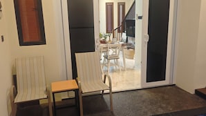 Une pièce avec une piscine, deux chaises, une table et une porte coulissante donnant sur un escalier.
