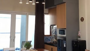 Une cuisine moderne équipée d’un four à micro-ondes, d’un four et d’un évier. On y trouve une table à manger avec des chaises et un banc.