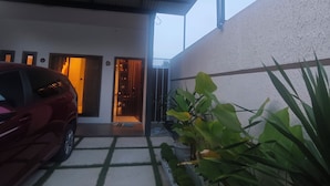 Un bâtiment moderne avec une voiture garée devant. On y voit des plantes et un portail menant à l’entrée.