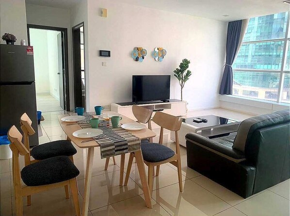 A modern living room with a dining area, a flat-screen TV, and a sofa. - Bright 2BR Suasana Near JB Sentral CIQ (Johor Bahru)
