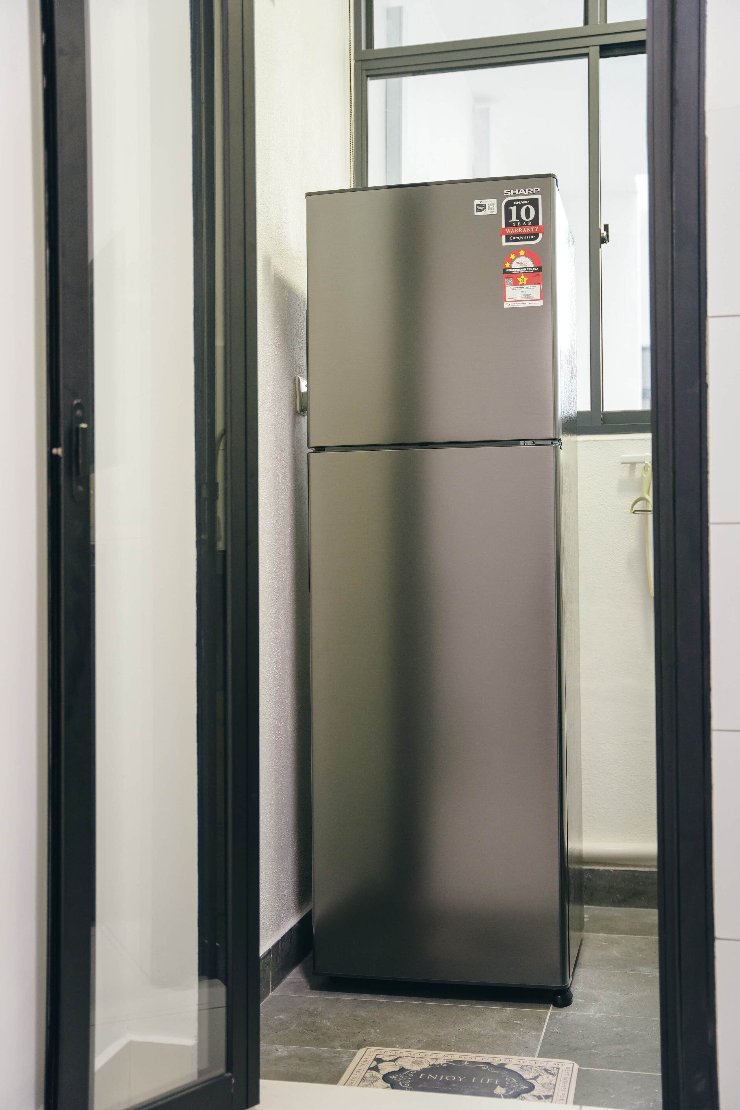 A stainless steel refrigerator in a room with a tiled floor and a window.