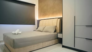 A modern bedroom with a bed, a nightstand, and a wardrobe.