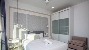 Ein modernes Hotelzimmer mit einem großen Bett, einem Nachttisch, einer Sitzecke und einem Kleiderschrank.