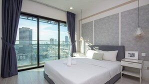 Ein modernes Hotelzimmer mit einem großen Bett, einem Nachttisch, einem Schreibtisch und Blick auf die Stadt durch raumhohe Fenster.