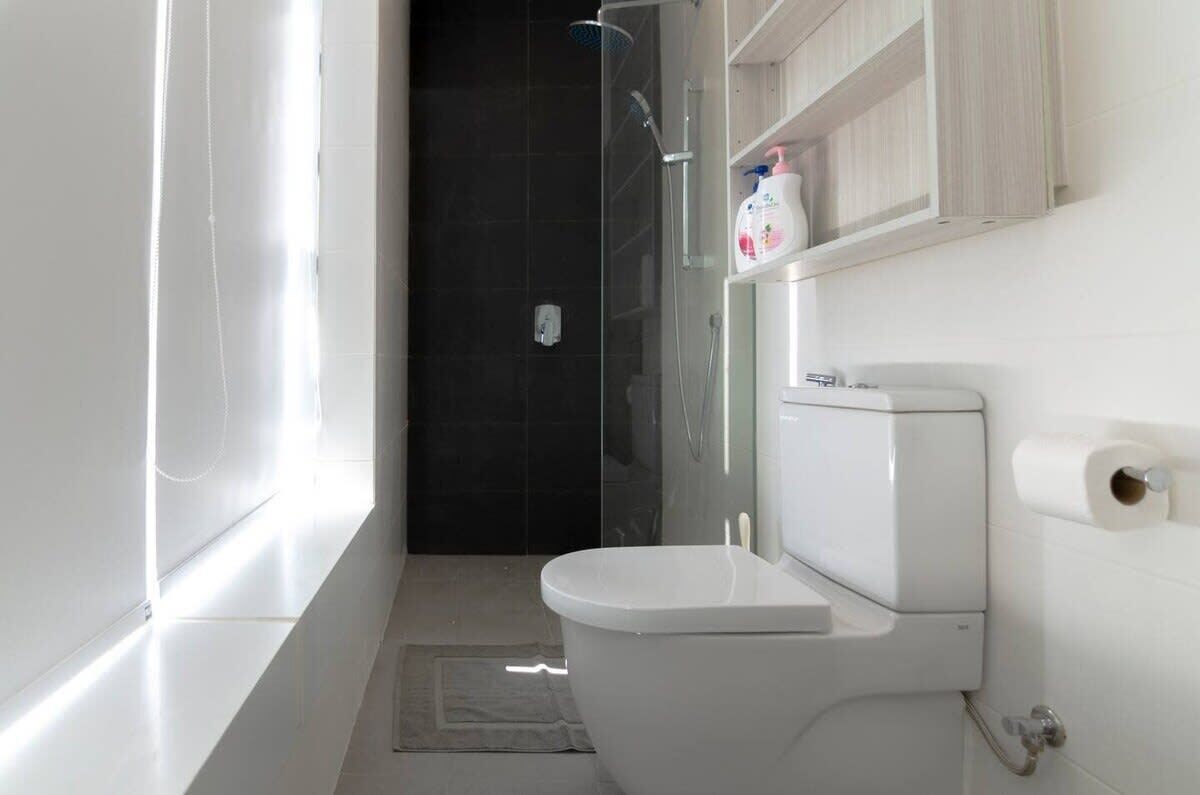 A modern bathroom with a toilet, a shower, and a glass-enclosed shower area.