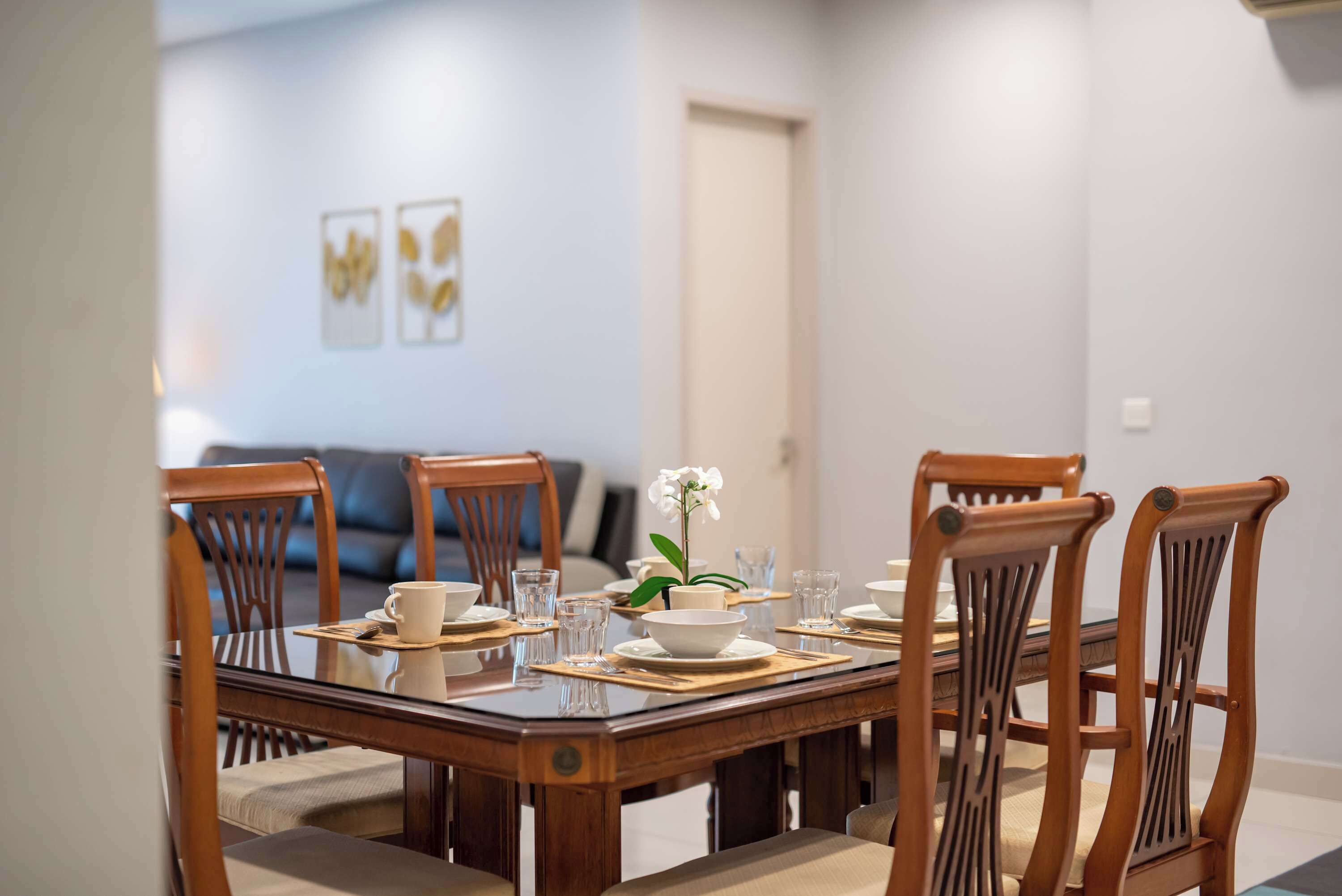 A dining table set with chairs, a vase with flowers, and a bowl.