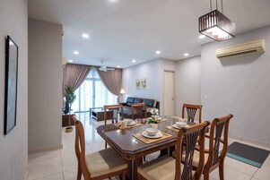 Un comedor con una mesa rectangular dispuesta para cuatro personas, rodeada de sillas de madera con asientos acolchados.