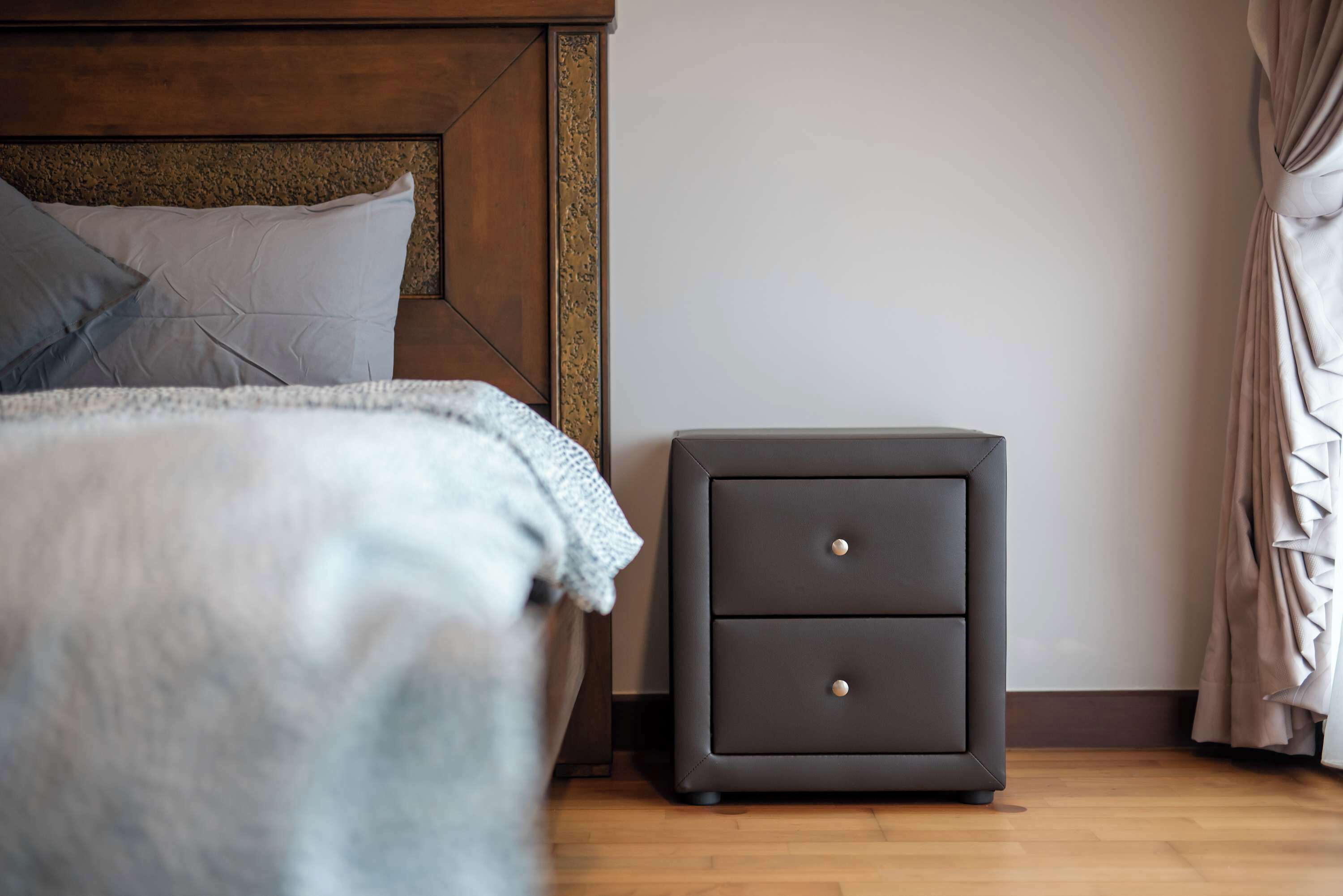 Un dormitorio con cama, mesita de noche y cabecera de madera.