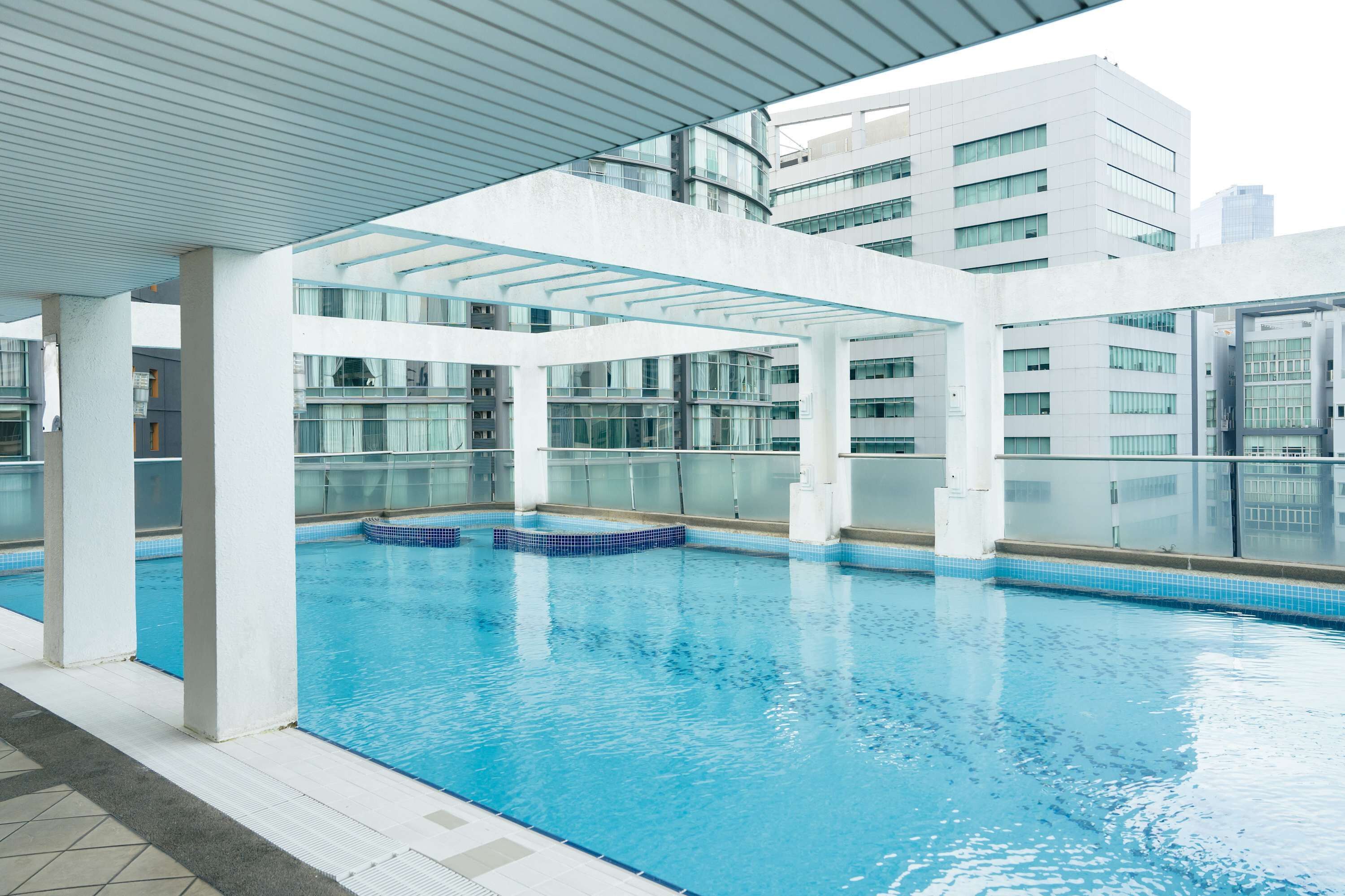 An indoor swimming pool with clear glass walls, a tiled floor, and a modern architectural design.
