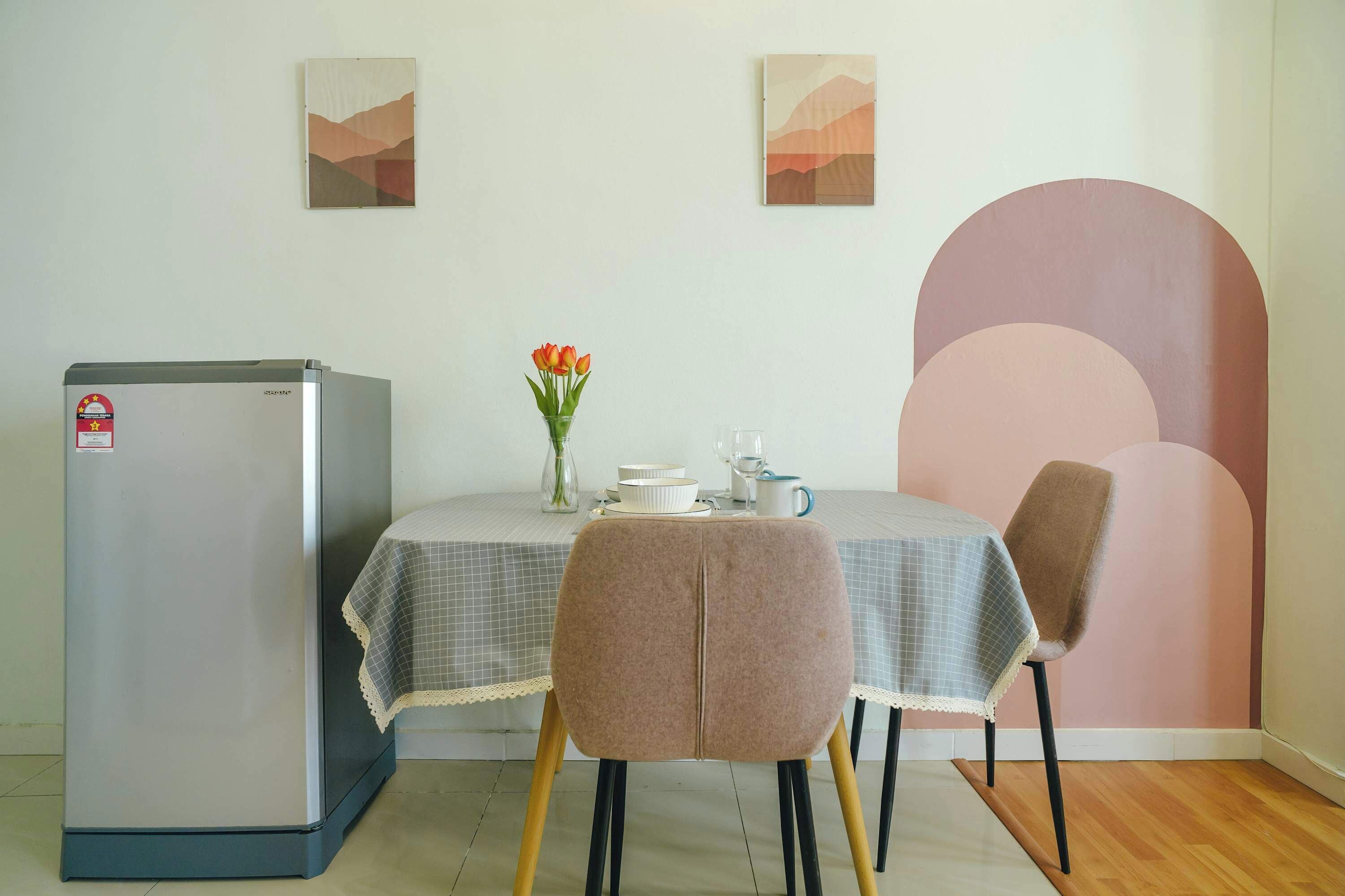 Een eetruimte met een tafel, stoelen, een koelkast en wanddecoratie.