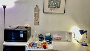 A kitchen area with a microwave, coffee maker, and a framed artwork of a tree.