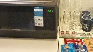 A microwave with a Kenmore label, a small figurine of two bunnies, a framed picture, and a wall-mounted sign with the word 'Thankful.'