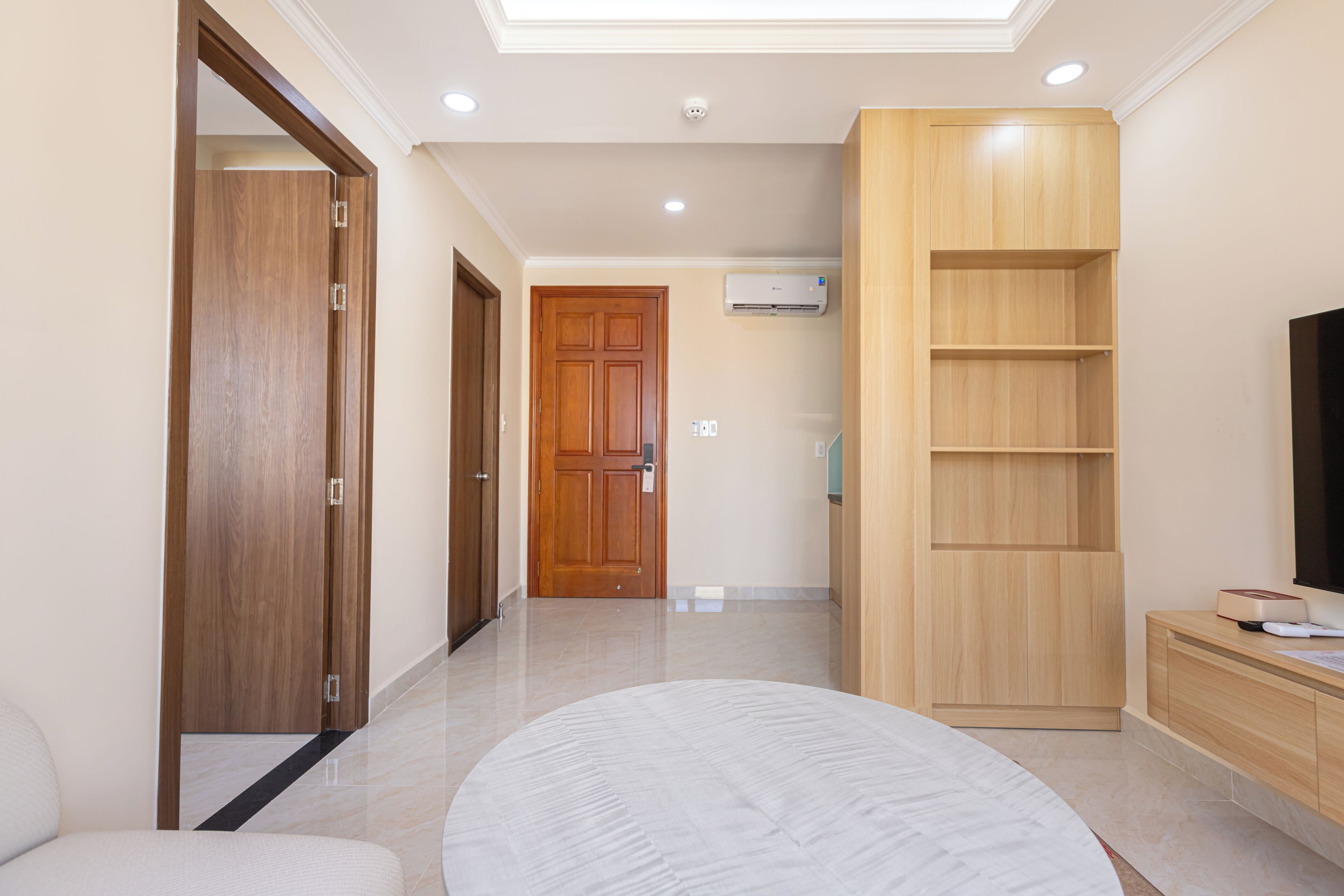 A hotel room with a large bed, a wooden wardrobe, a TV stand, and a built-in shelf unit.