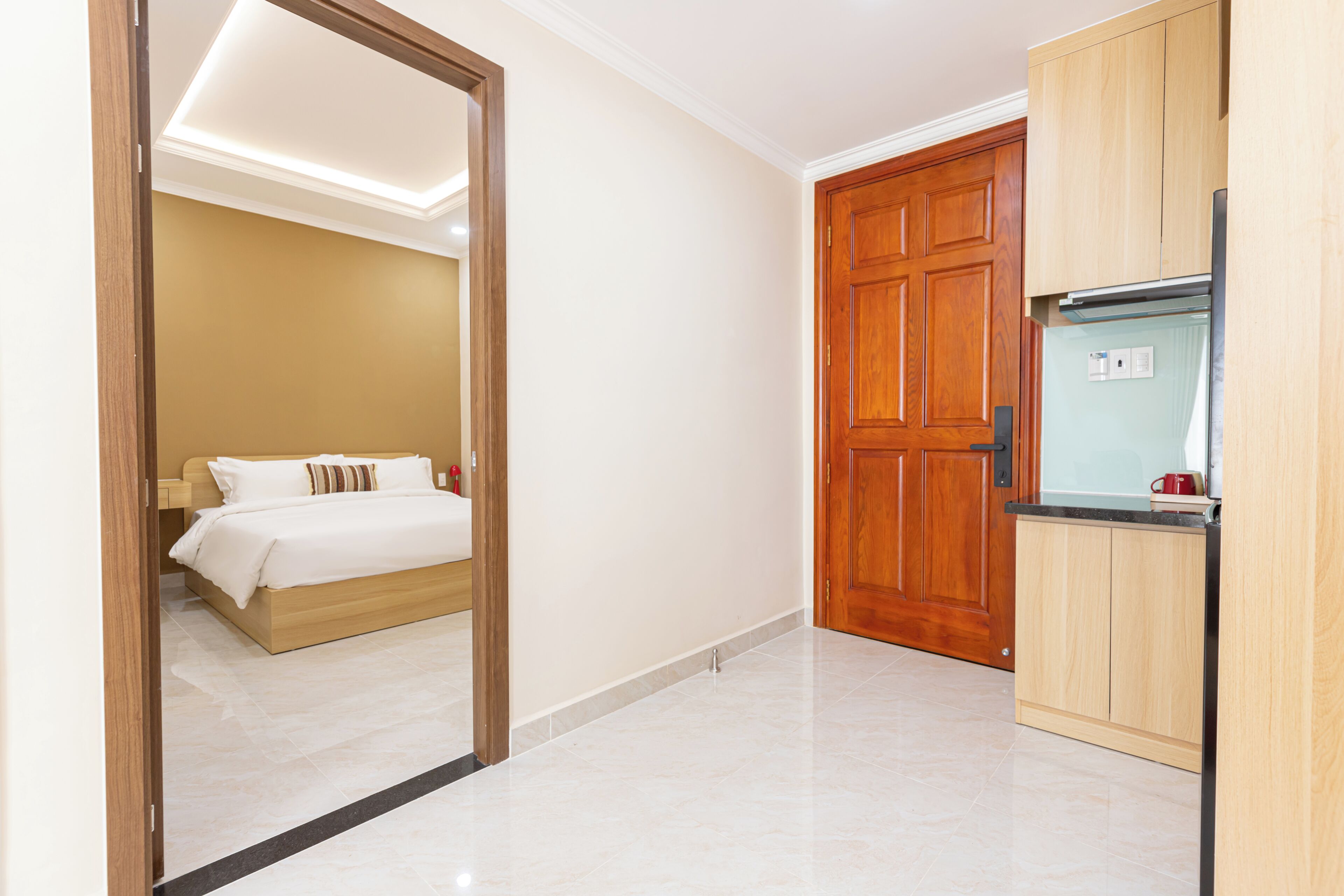 A hotel room with a bed, a wooden wardrobe, and a kitchen area.