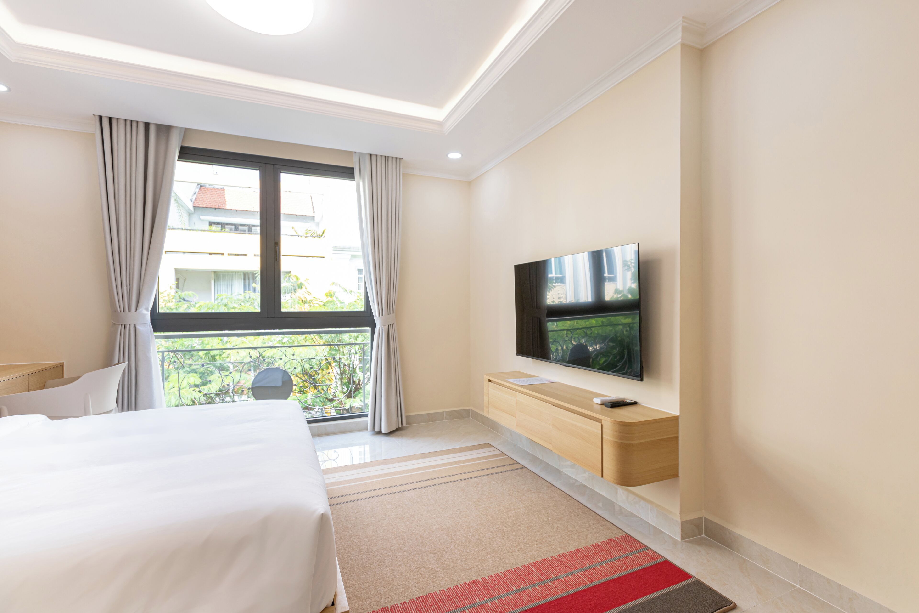A hotel room with a bed, a TV, a wooden cabinet, and a window with curtains.