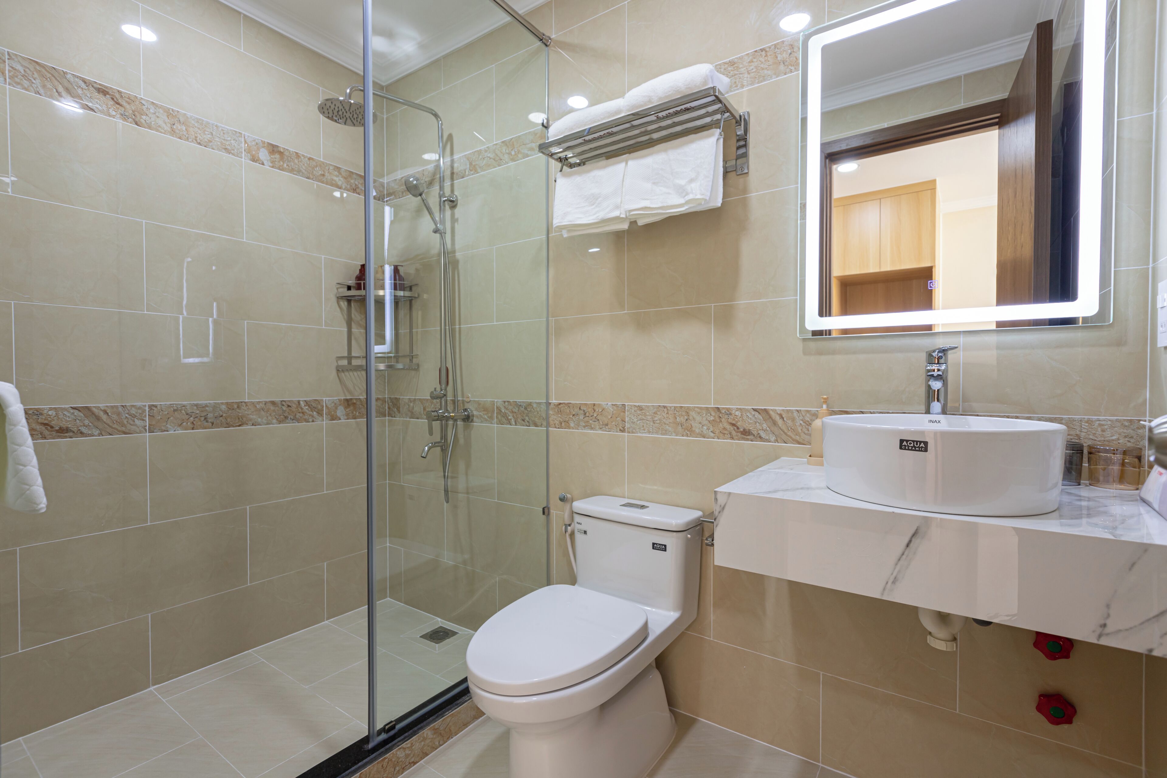 A modern bathroom with a glass-enclosed shower, a white toilet, and a marble countertop with a sink.