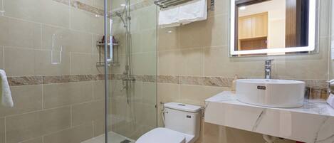 A modern bathroom with a glass-enclosed shower, a white toilet, and a marble countertop with a sink.