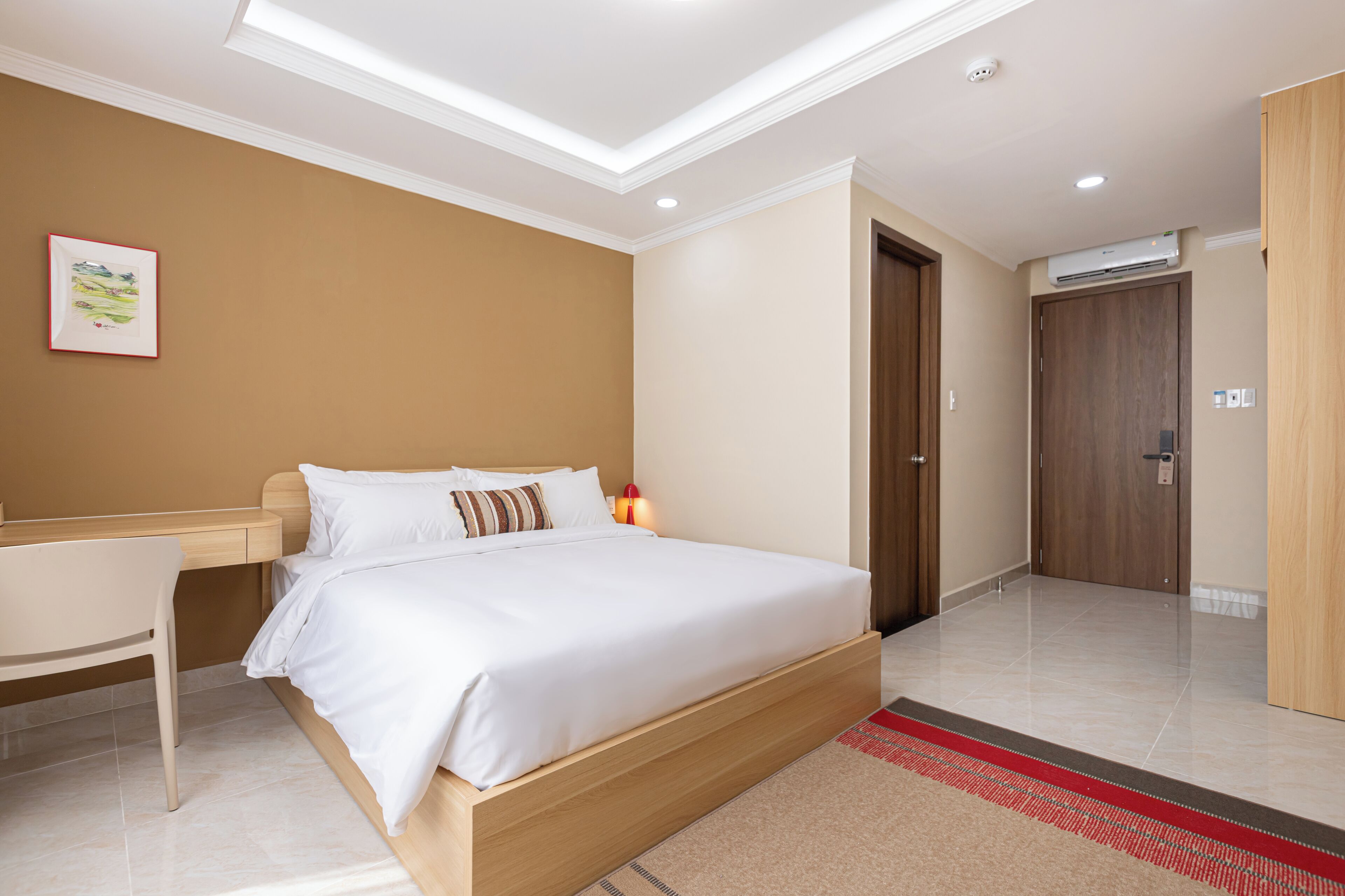 A modern hotel room with a large bed, a desk, and a door leading to another room.