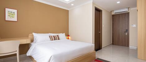 A modern hotel room with a large bed, a desk, and a door leading to another room.