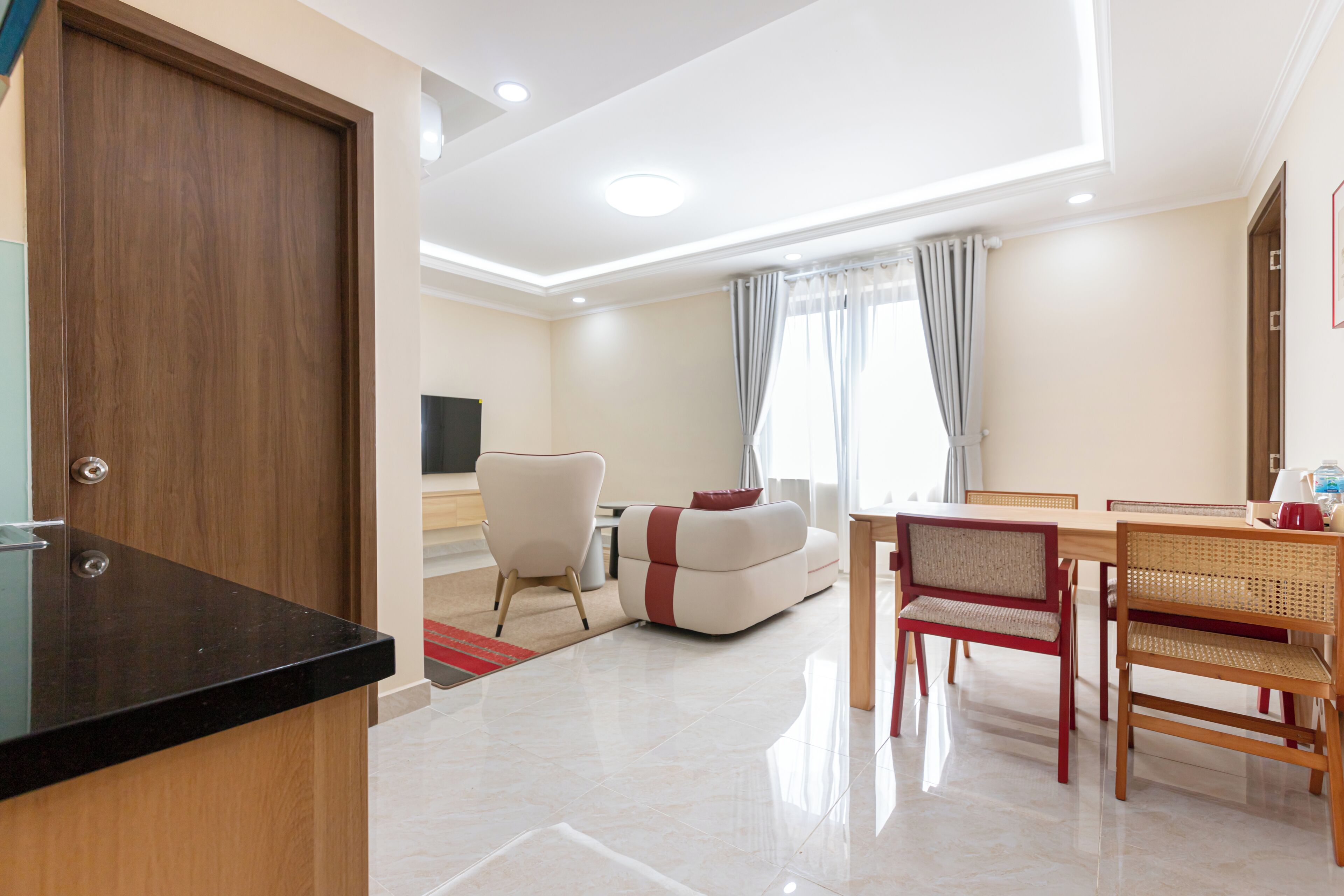 A modern living room with a sofa, a dining table with chairs, and a TV.