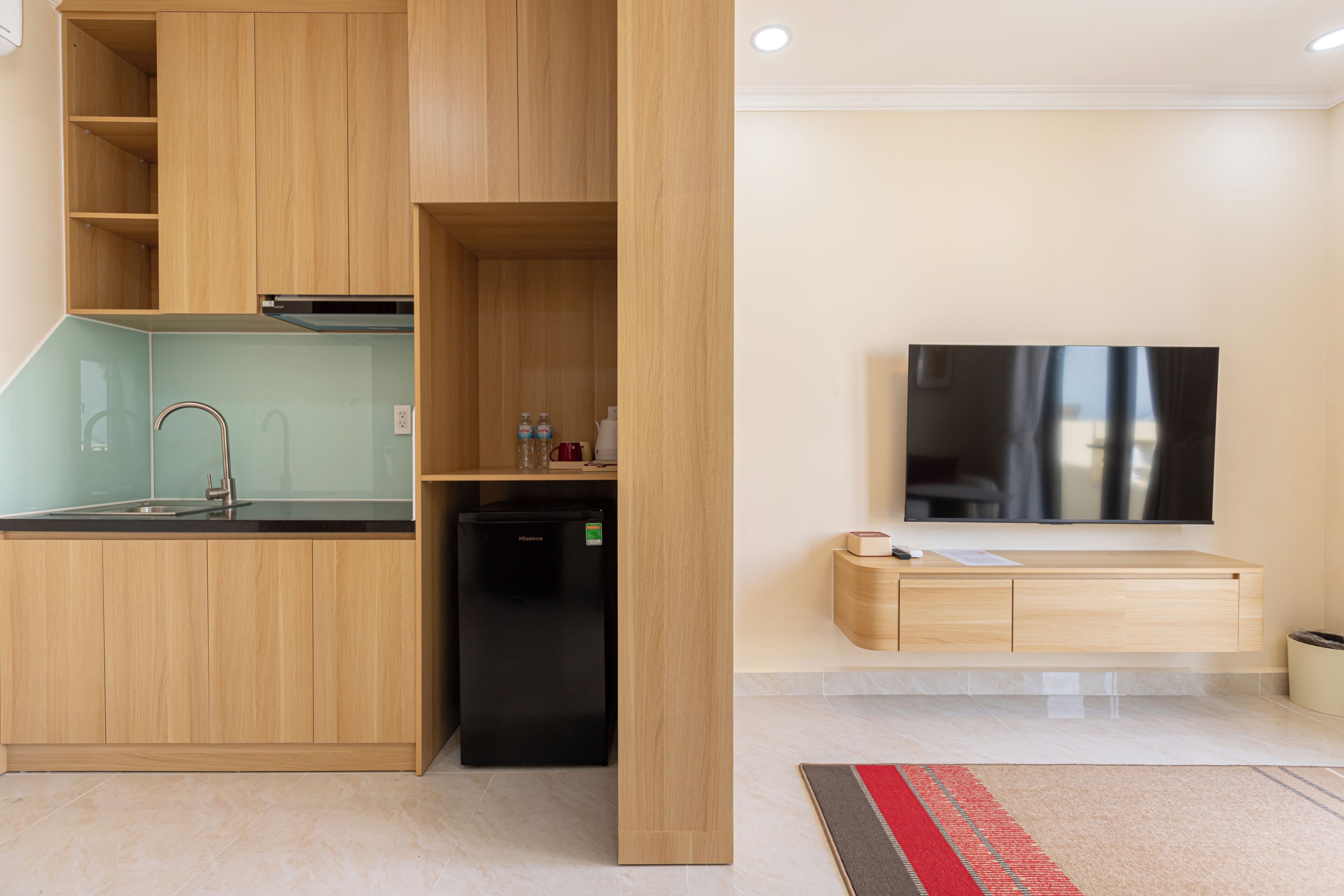 Une cuisine moderne avec des meubles en bois, un réfrigérateur noir et une cuisinière encastrée.