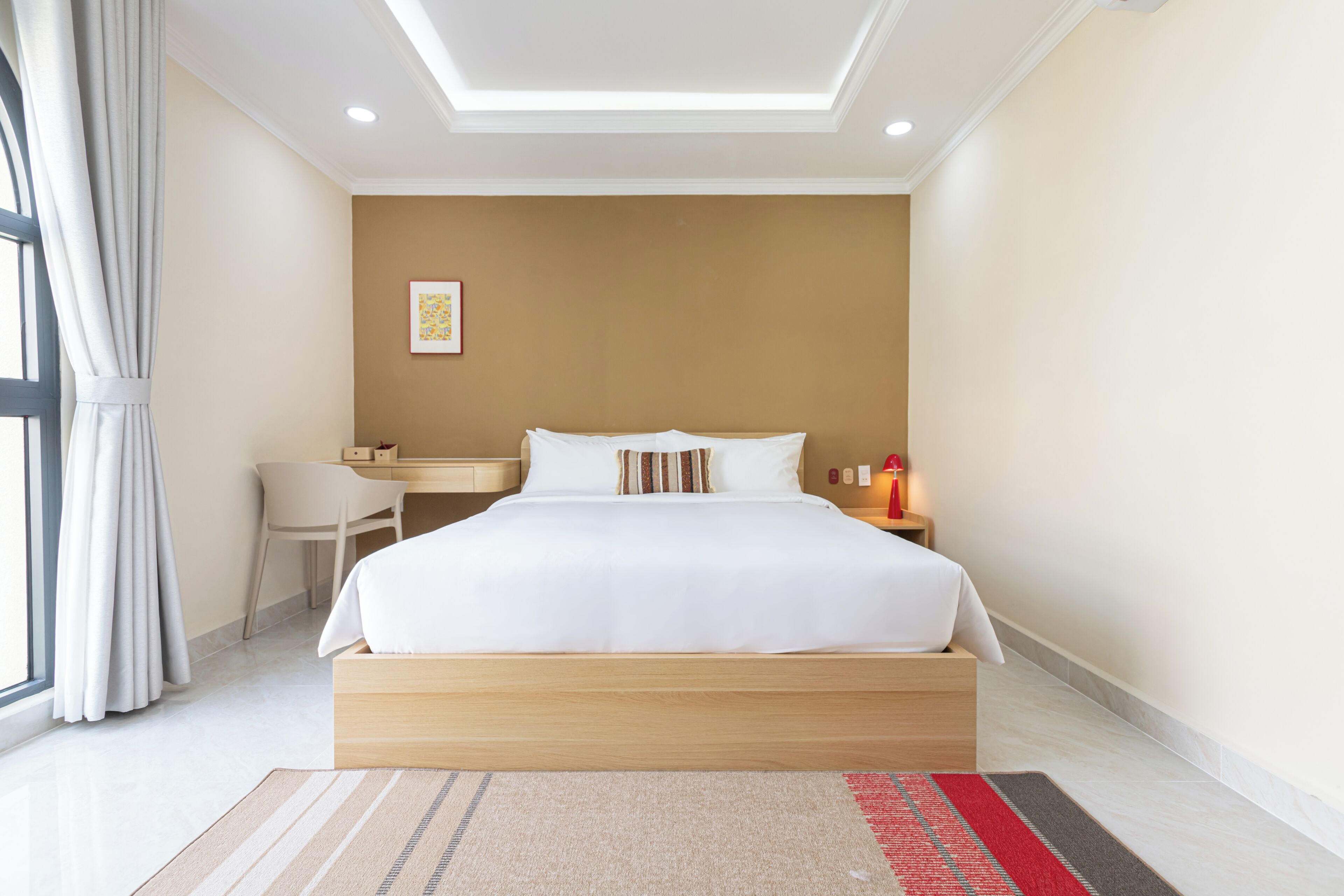 Een moderne hotelkamer met een groot bed, een bureau en een stoel.