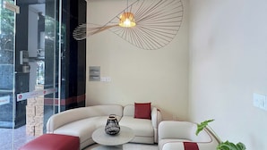 Un salon moderne avec un canapé d’angle, une table basse et un luminaire suspendu original.