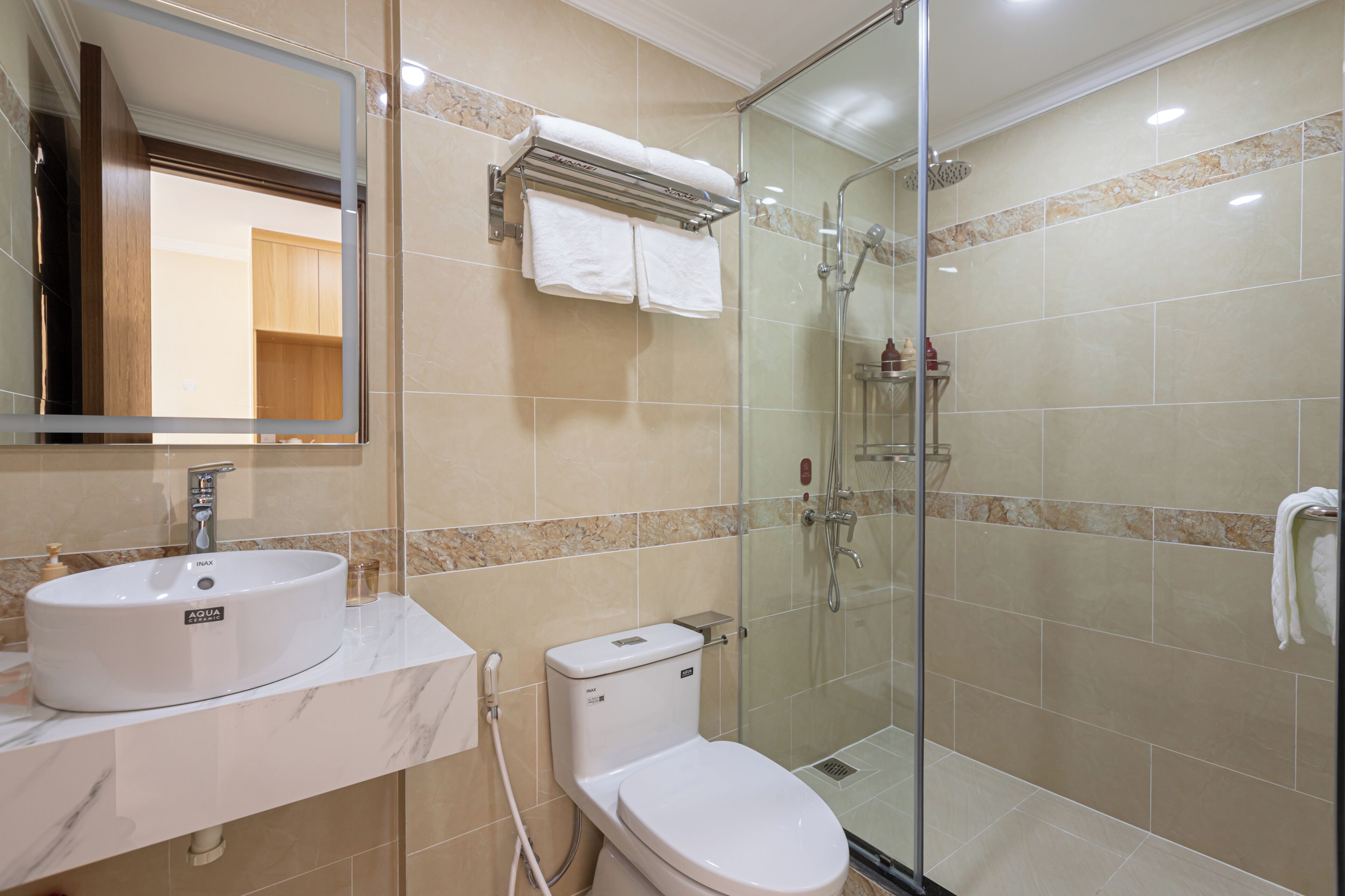 A modern bathroom with a glass-enclosed shower, a white sink, and a toilet.