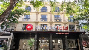 L’extérieur de l’hôtel Shankee se distingue par une grande enseigne rouge, de larges fenêtres et un balcon.