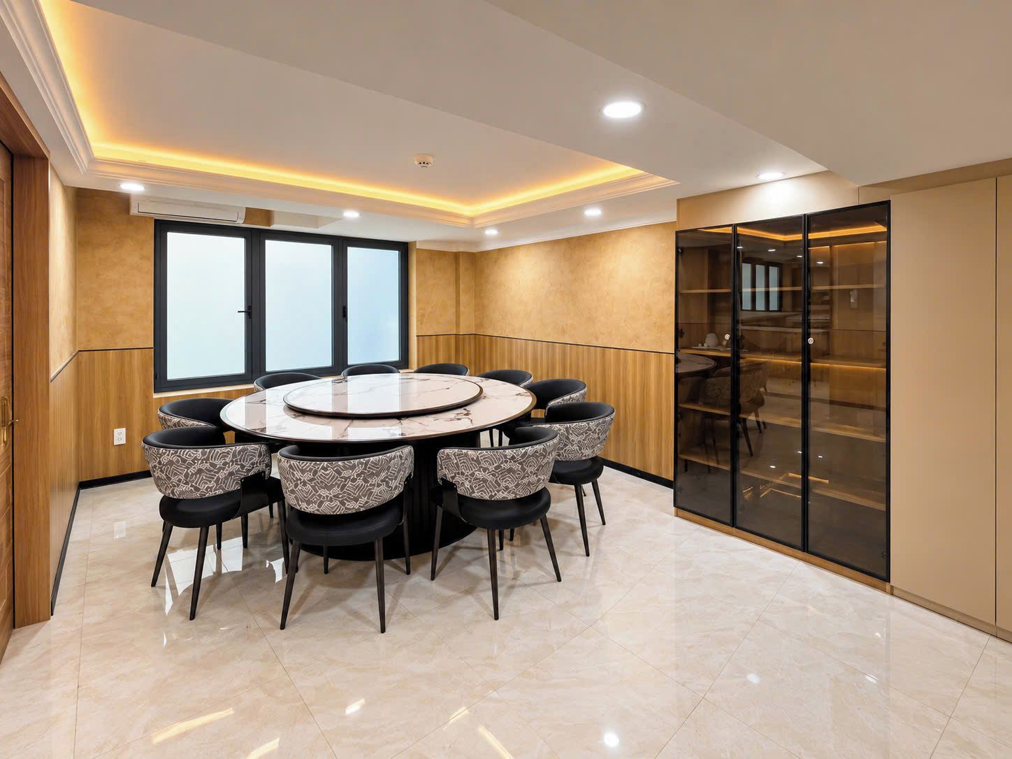 A modern conference room with a round table, black and patterned chairs, and a large window.