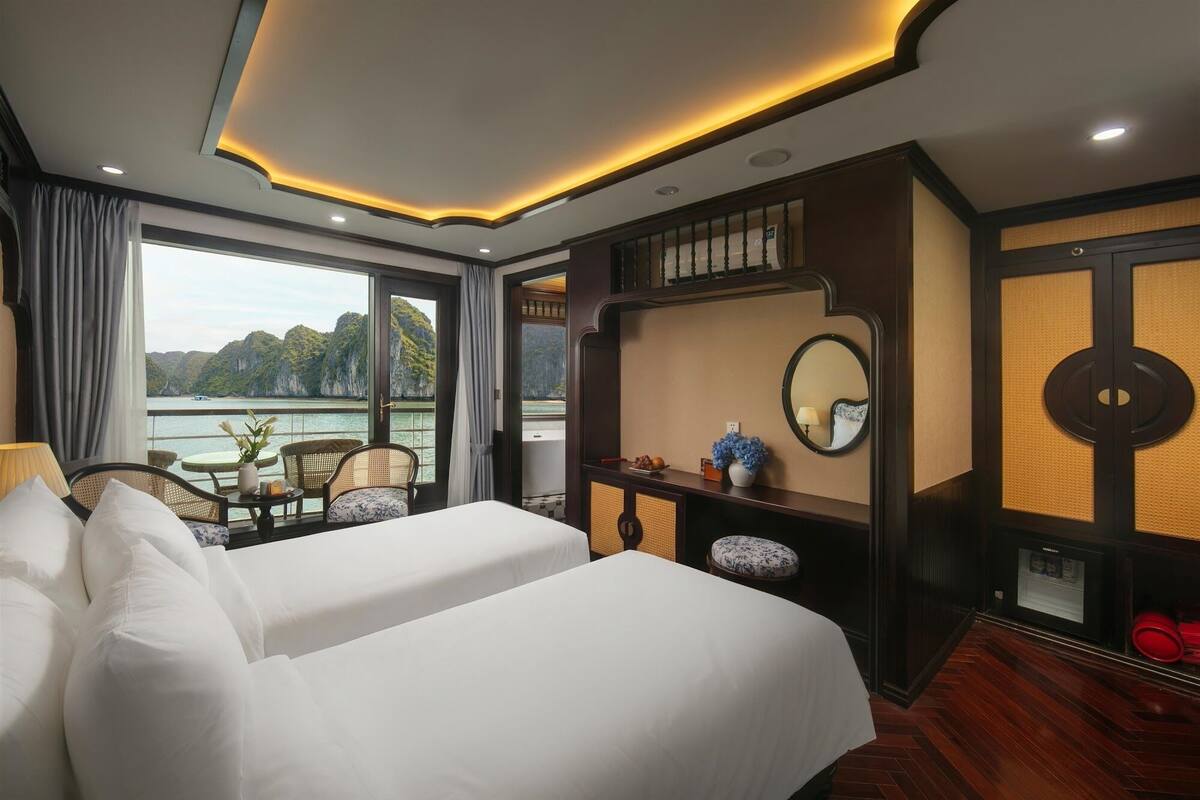 A hotel room with a large bed, a desk with a chair, a view of the sea, and a balcony.
