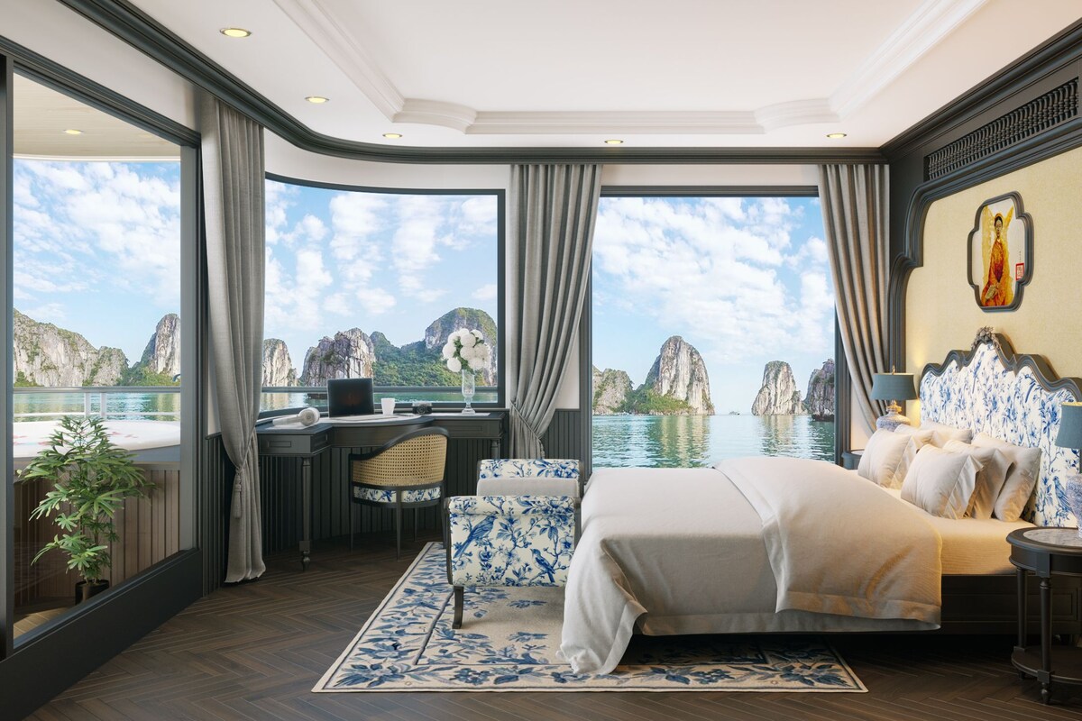 A luxurious bedroom with a large bed, a desk, and a view of the sea.