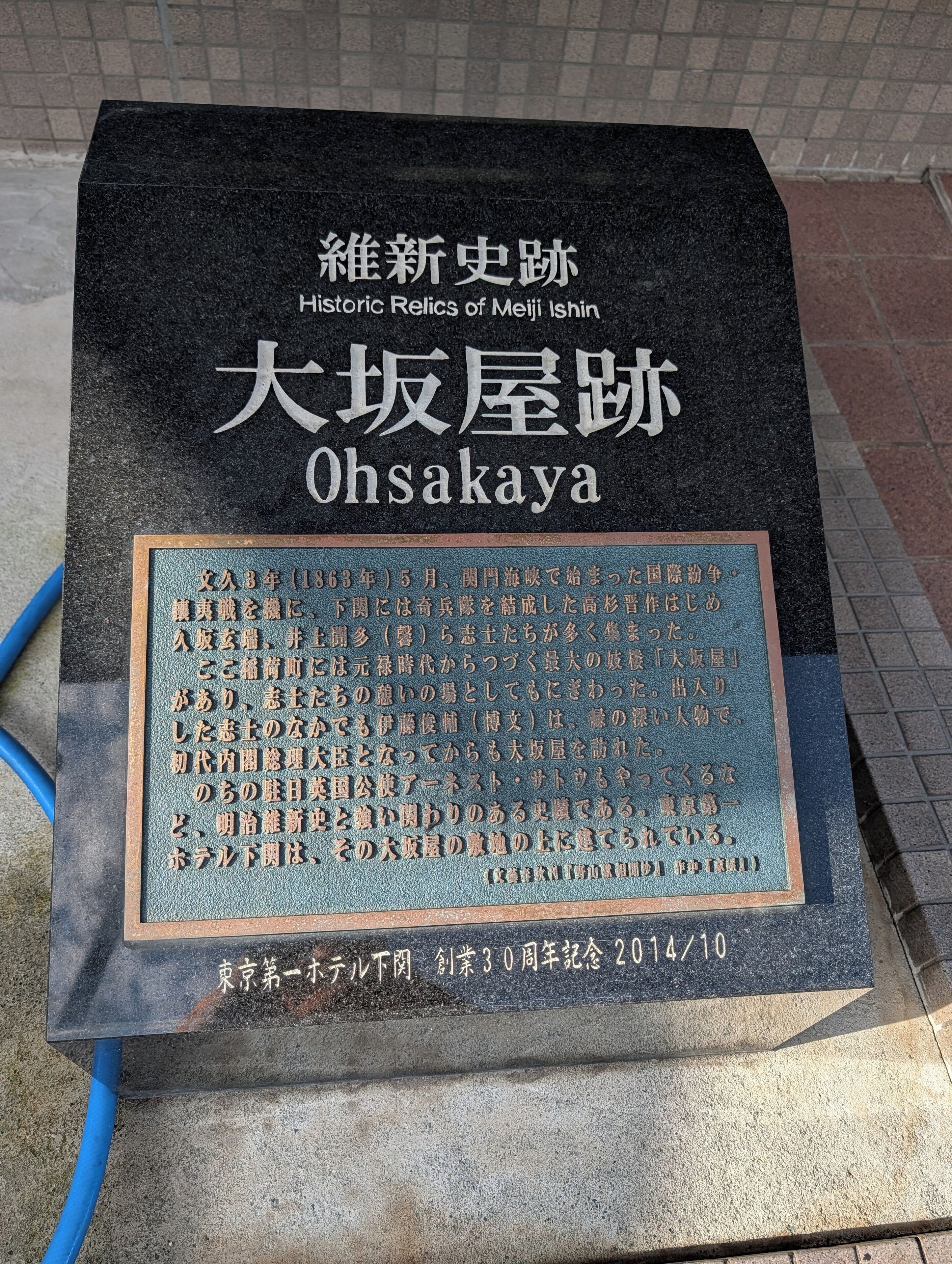 A stone monument with inscriptions, including 'Historic Relics of Meiji Ishin' and 'Ohsakaya.'