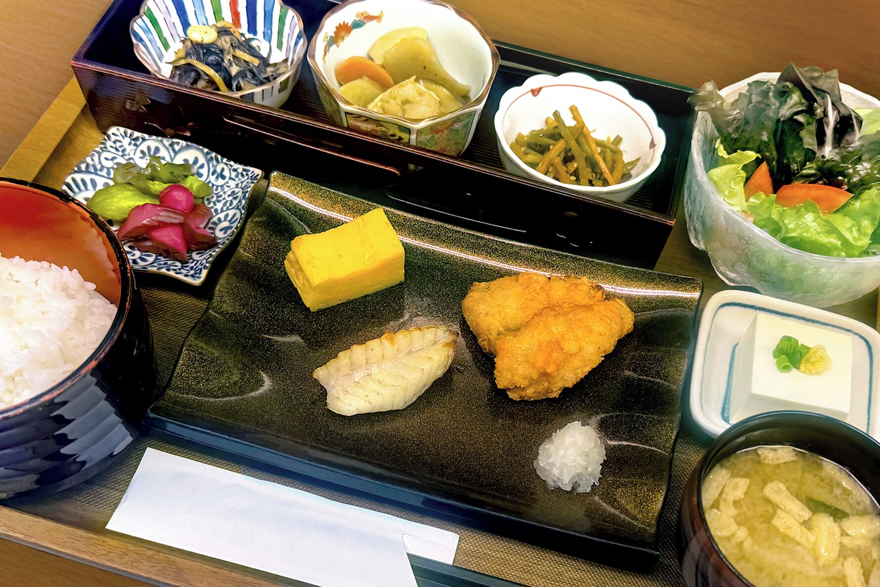 A tray with various Japanese dishes including rice, fish, and vegetables.