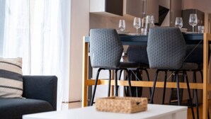 A modern living room with a sofa, a dining table with chairs, and a small table with a basket.