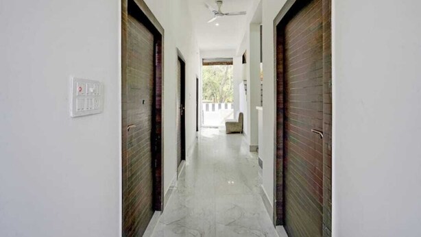 A hallway with a ceiling fan, a light switch, and a view of the outside. - Hotel River View & Restaurant (Hathras)