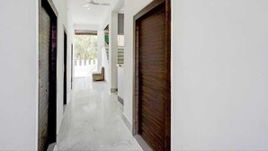 A hallway with a tiled floor, a ceiling fan, and a view of the outside. - Hotel River View & Restaurant (Hathras)