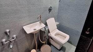 A bathroom with a toilet, sink, and bidet. - Hotel River View & Restaurant (Hathras)