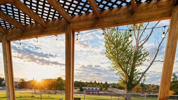An outdoor patio with wicker furniture, a pergola, and a view of a farm. -  Stable House INN - Pool - Horse Farm - Hot Tub - Near Smith Rocks State Park (Redmond)