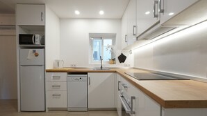 A modern kitchen with white cabinetry, a wooden countertop, a microwave, a dishwasher, and a window with a view. - La Casita Fuengirola - Charming 3 bed ground floor (Fuengirola)