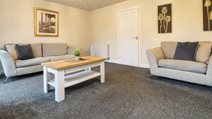 Ein Wohnzimmer mit zwei Sofas, einem Couchtisch, einer Heizung und einer Tür.
