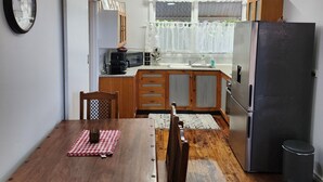 Eine kleine Küche mit Holzschränken, einem Kühlschrank und einem Esstisch mit Stühlen.