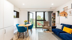 Un salon moderne avec un coin repas, un canapé bleu et une bibliothèque.