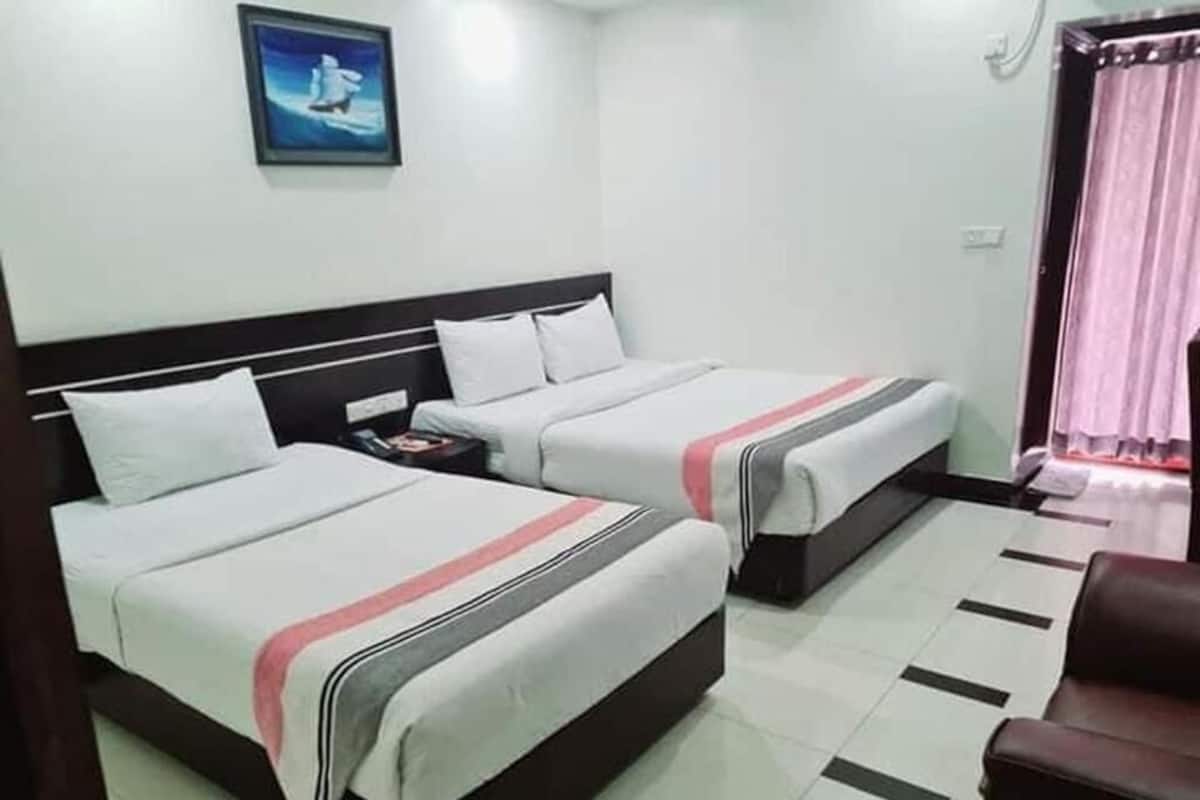 A hotel room with two beds, a nightstand, a chair, and a painting on the wall.